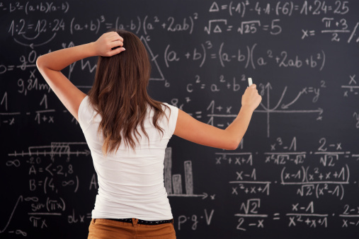 Young woman looking at math problem on blackboard